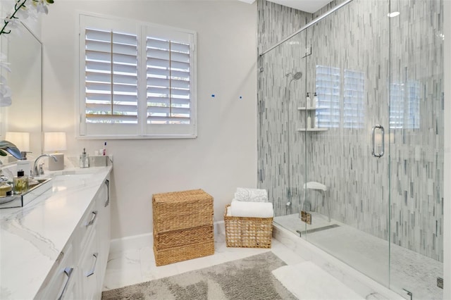 bathroom featuring marble finish floor, vanity, baseboards, and a stall shower