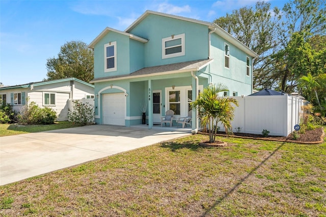 traditional home with stucco siding, a porch, concrete driveway, a front yard, and fence