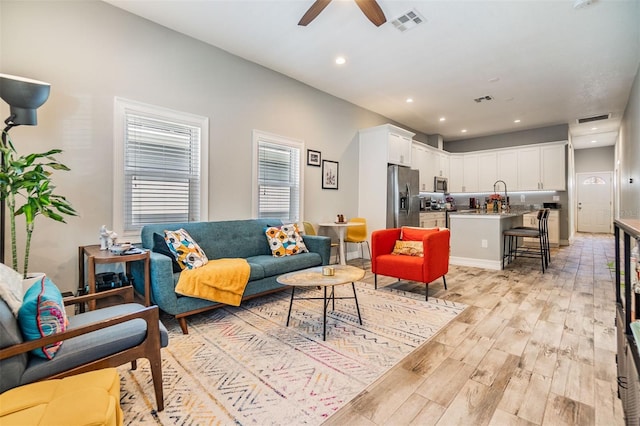 living room featuring ceiling fan, light wood-type flooring, visible vents, and recessed lighting