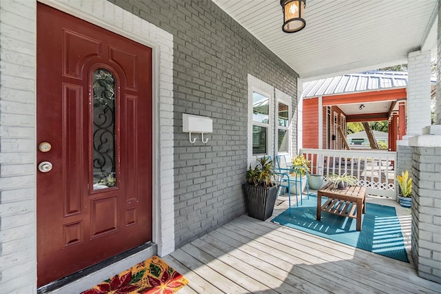 property entrance with covered porch and brick siding