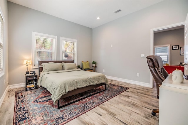 bedroom featuring light wood-style floors, baseboards, multiple windows, and visible vents