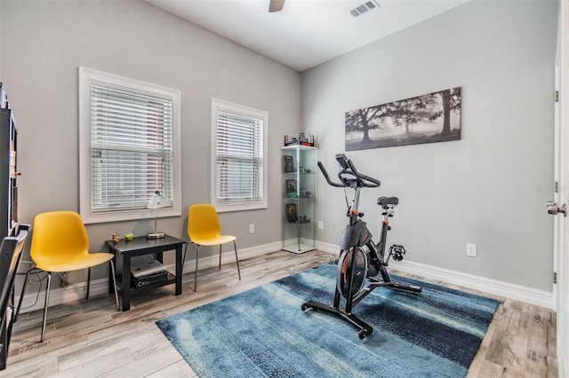 exercise area featuring a ceiling fan, baseboards, visible vents, and wood finished floors