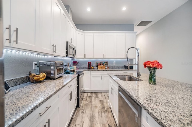 kitchen featuring stainless steel appliances, a sink, visible vents, and white cabinets