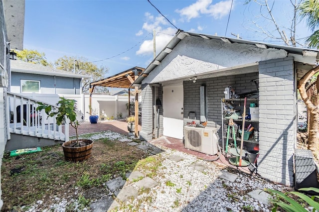 rear view of house with brick siding, ac unit, fence, and a patio