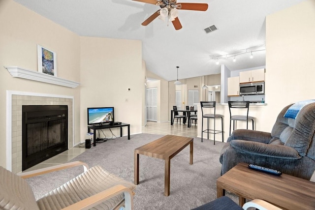 living area with light carpet, a fireplace, visible vents, and vaulted ceiling