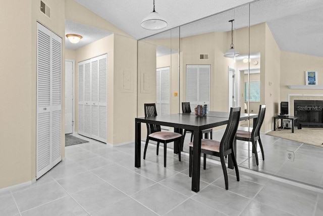 tiled dining room featuring lofted ceiling, a tiled fireplace, and visible vents