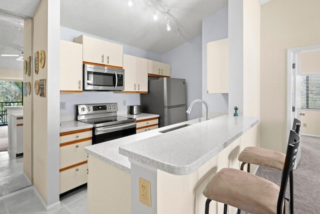 kitchen with stainless steel appliances, a sink, ceiling fan, a peninsula, and a kitchen breakfast bar