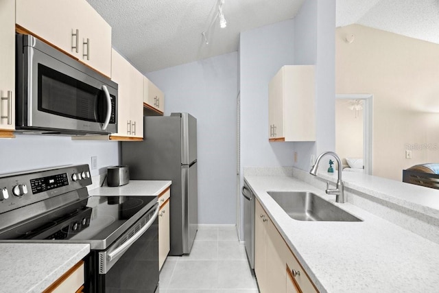 kitchen featuring a textured ceiling, stainless steel appliances, a sink, vaulted ceiling, and light countertops