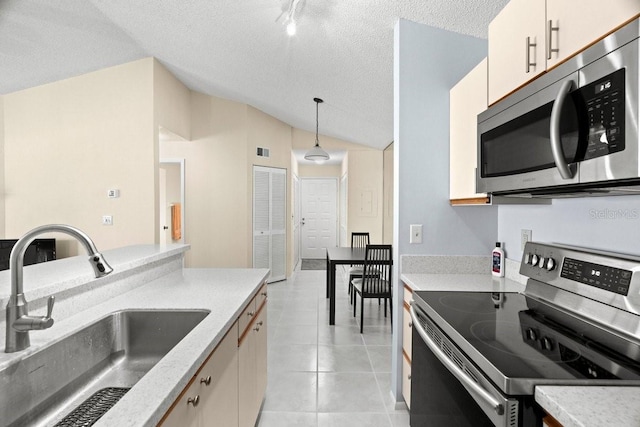 kitchen with light tile patterned floors, stainless steel appliances, a sink, vaulted ceiling, and hanging light fixtures