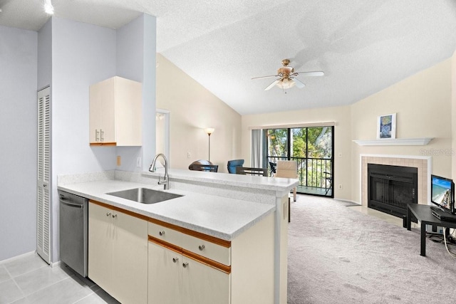 kitchen featuring lofted ceiling, light countertops, stainless steel dishwasher, and a sink