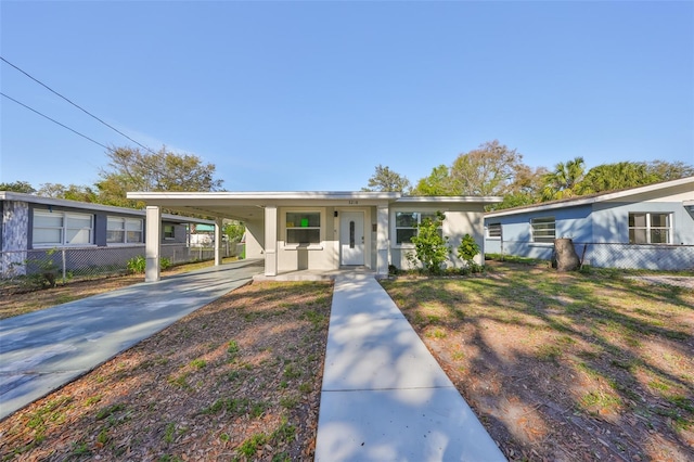 view of front of property with concrete driveway, an attached carport, fence, and stucco siding