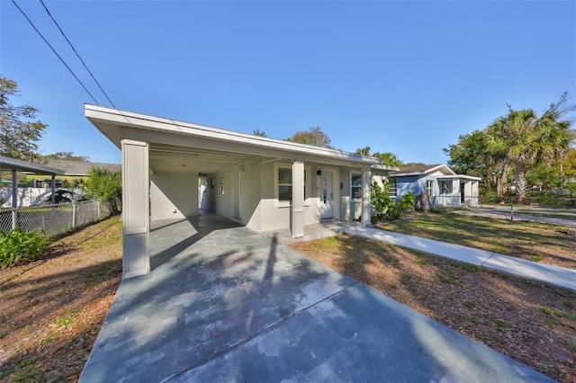 view of front of property featuring driveway, fence, a front lawn, a carport, and stucco siding