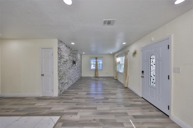 entrance foyer with baseboards, visible vents, a textured ceiling, and wood finished floors