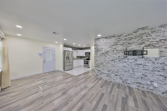 unfurnished living room featuring light wood-style flooring, visible vents, and recessed lighting