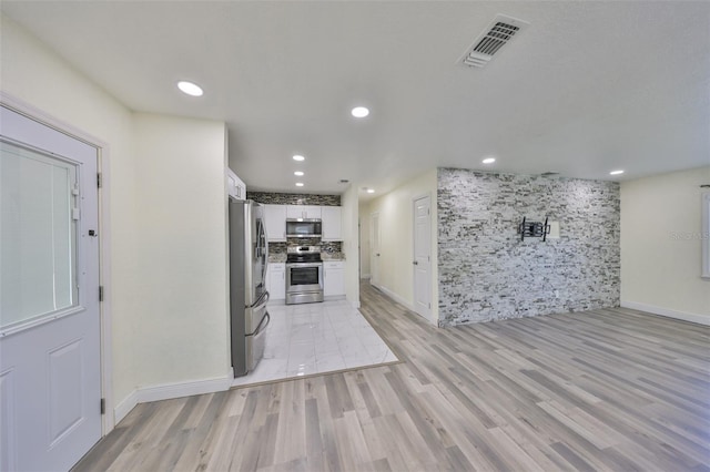 kitchen featuring visible vents, white cabinets, decorative backsplash, appliances with stainless steel finishes, and light wood-style floors