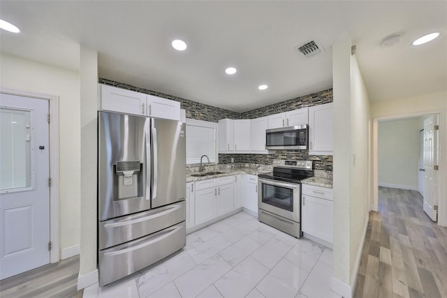 kitchen featuring marble finish floor, visible vents, appliances with stainless steel finishes, white cabinets, and a sink