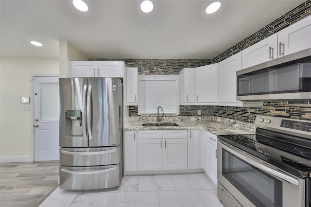 kitchen with appliances with stainless steel finishes, white cabinetry, a sink, and backsplash