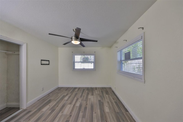 unfurnished bedroom with multiple windows, baseboards, and wood finished floors