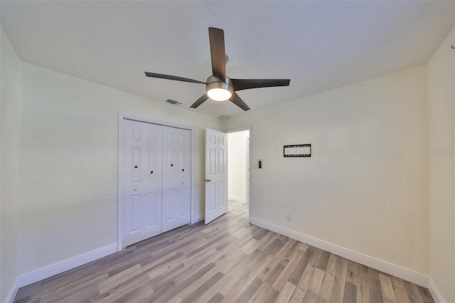 unfurnished bedroom with light wood finished floors, baseboards, visible vents, and a closet