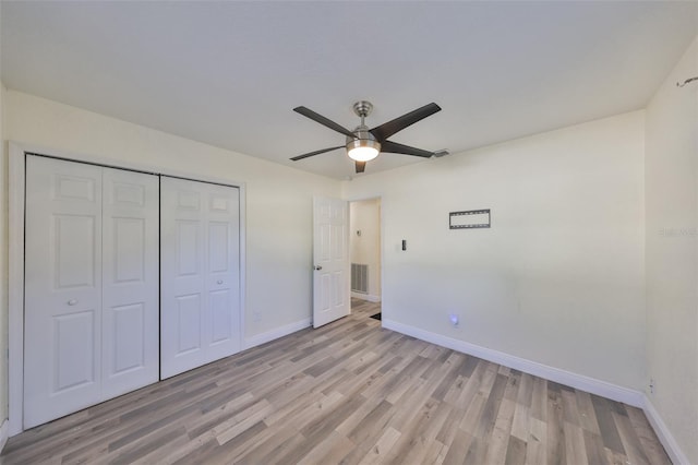 unfurnished bedroom featuring light wood finished floors, baseboards, visible vents, ceiling fan, and a closet