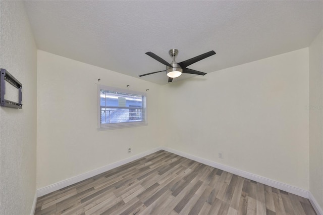 empty room featuring light wood-style flooring, baseboards, and a textured ceiling