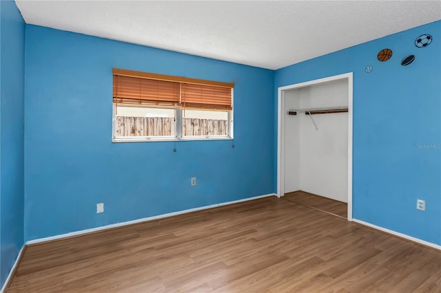 12704 128th Ln, Largo, FL 33774 - unfurnished bedroom featuring a textured ceiling, wood finished floors, baseboards, and a closet