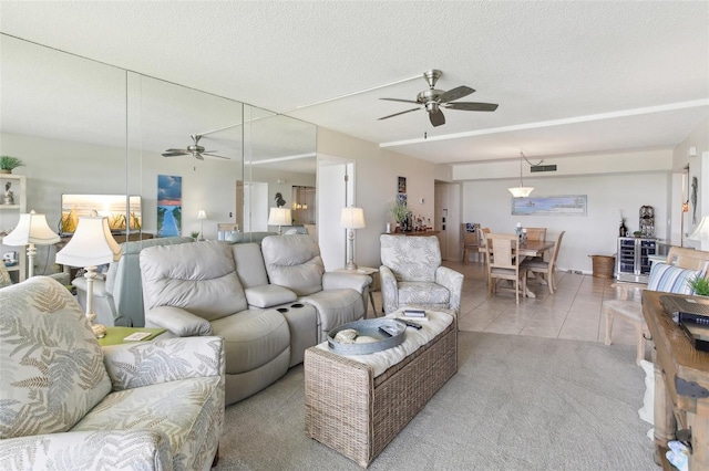 living room with carpet, ceiling fan, a textured ceiling, and tile patterned floors