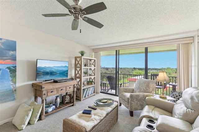 living room with a textured ceiling, ceiling fan, a wall of windows, and carpet