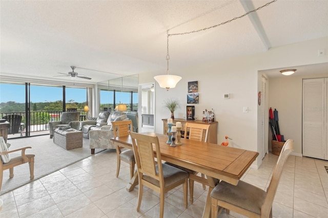 dining space featuring light tile patterned floors, baseboards, a wall of windows, and a ceiling fan