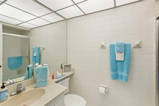 full bath with toilet, a shower stall, tile walls, and vanity