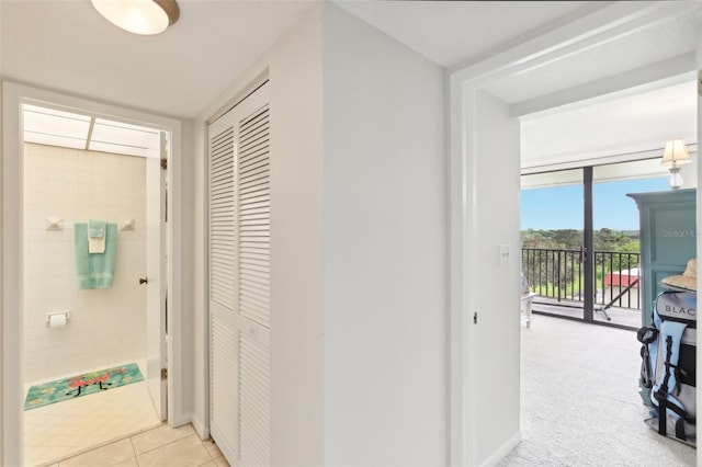 hallway with light carpet, light tile patterned flooring, and baseboards