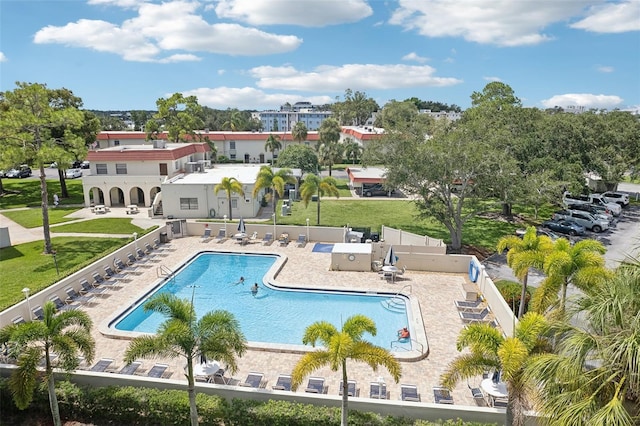 community pool featuring fence, a lawn, and a patio