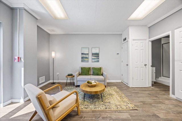 living area with baseboards, visible vents, and wood finished floors