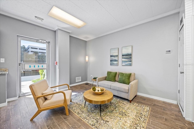 living room with ornamental molding, wood finish floors, visible vents, and baseboards