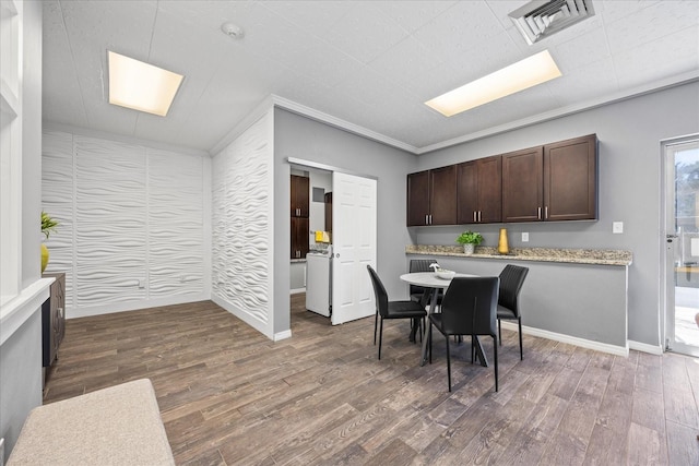 dining space featuring baseboards, crown molding, visible vents, and wood finished floors