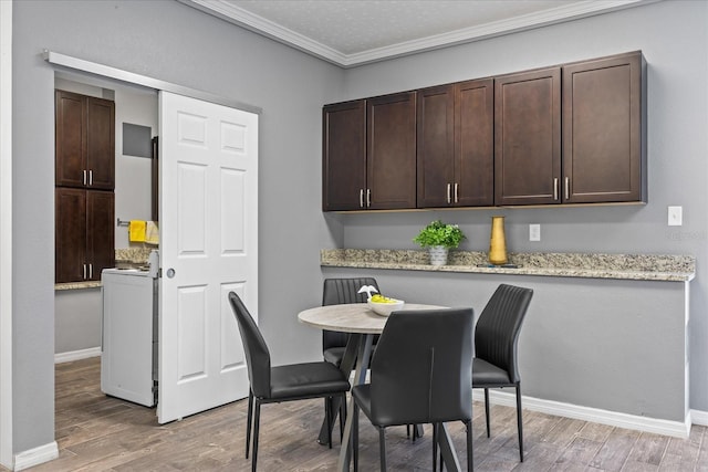 dining space featuring light wood-style flooring, washer / clothes dryer, baseboards, and ornamental molding