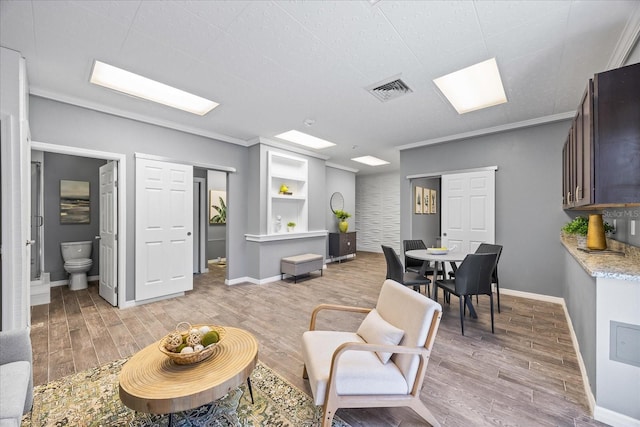 living room with visible vents, ornamental molding, light wood-style flooring, and baseboards