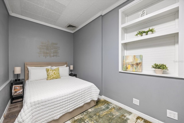 bedroom featuring ornamental molding, visible vents, baseboards, and wood finished floors