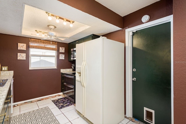 kitchen featuring white refrigerator with ice dispenser, a raised ceiling, light countertops, stainless steel microwave, and a textured ceiling