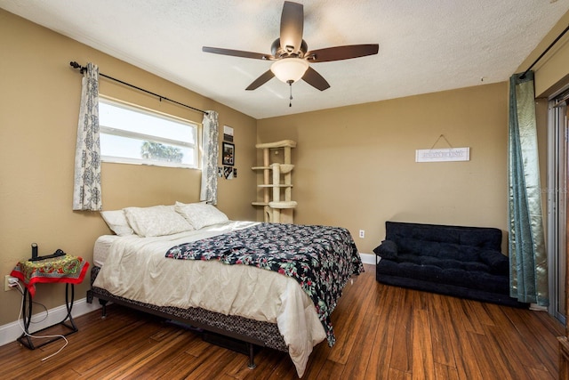 bedroom with a textured ceiling, baseboards, and wood finished floors