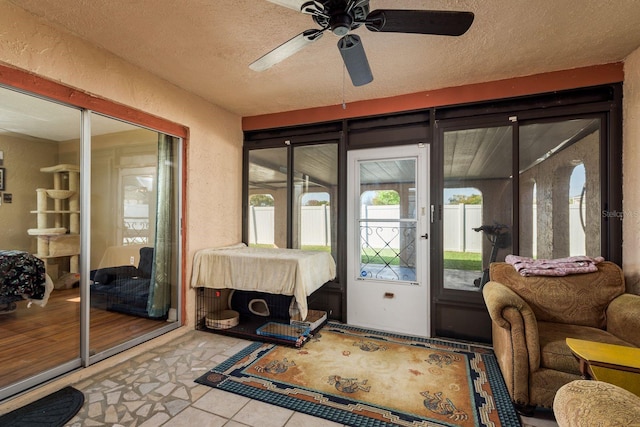 doorway to outside with a ceiling fan, a textured wall, a textured ceiling, and tile patterned floors