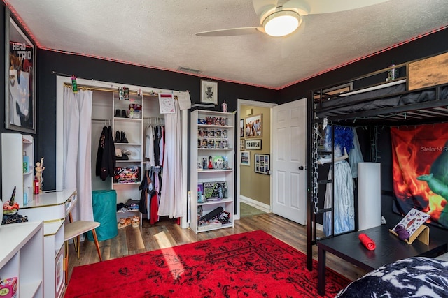 bedroom with visible vents, a ceiling fan, wood finished floors, a textured ceiling, and a closet