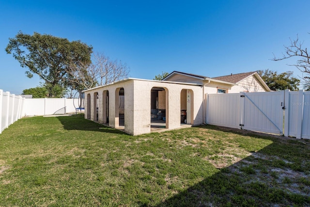 exterior space with a fenced backyard, a gate, a lawn, and stucco siding