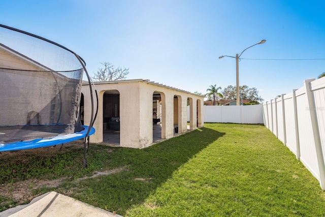 view of yard with a patio area, a fenced backyard, and a trampoline