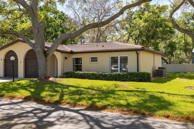 view of front of home with a garage, central AC, fence, and a tiled roof