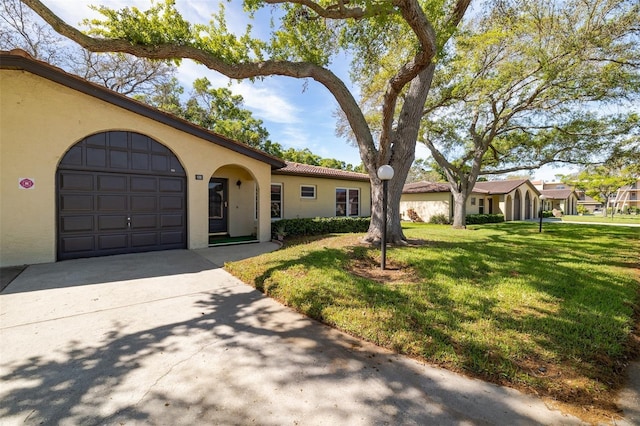 view of front of home with an attached garage, a tile roof, concrete driveway, stucco siding, and a front lawn