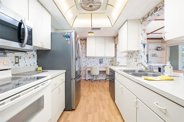 kitchen featuring light wood finished floors, appliances with stainless steel finishes, light countertops, and a sink