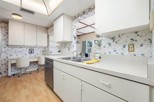 kitchen with light wood-style flooring, a sink, light countertops, stainless steel dishwasher, and wallpapered walls