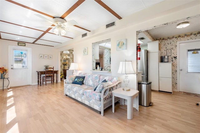 living area featuring light wood-style flooring, ceiling fan, beamed ceiling, baseboards, and wallpapered walls