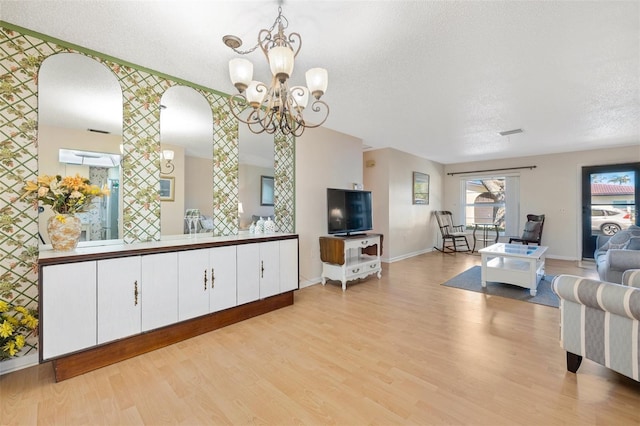 living area with baseboards, visible vents, light wood-style flooring, and a textured ceiling